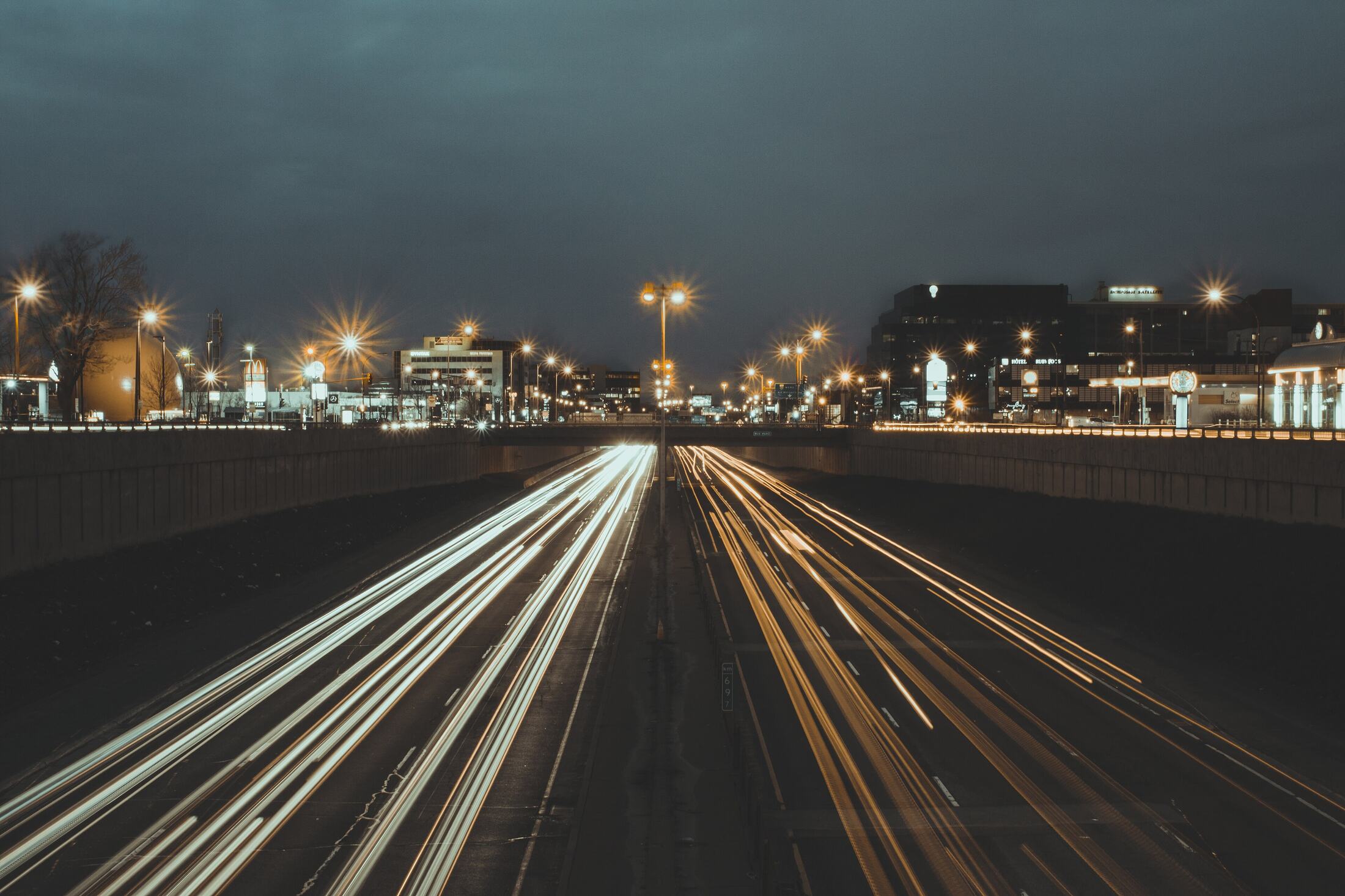 Long-exposure streaks of headlights and tail lights on an expressway at night.